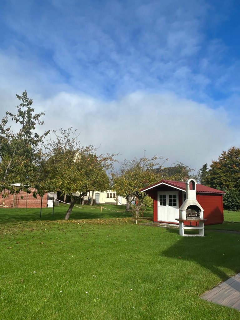 Garten der Ferienwohnung Zur Mühle in Burhave mit Wiese, Apfelbäumen und Gartenhaus